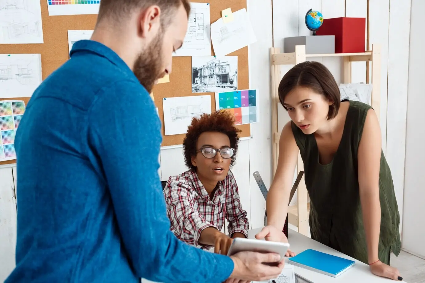 사무실에서 동료들이 태블릿을 보며 새로운 아이디어를 논의하고 있다.