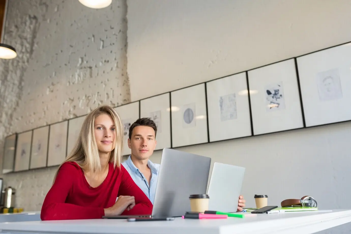 오픈형 코워킹 오피스 공간에서 젊은 남성과 여성이 노트북으로 작업하고 있다.